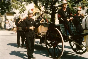 Archive des 110 ans du corps des sapeurs-pompiers en 1985. Défilé sur le char à banc tirant la pompe à bras comme à la fin du 19e siècle et au début du 20e siècle.