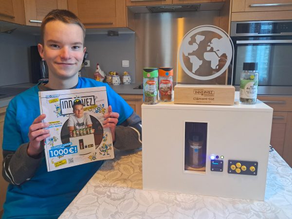 Clément, tenant fièrement la page qui lui a été dédiée dans le magazine Science & Vie Junior, et son Distri-épices sur lequel il a posé son trophée.