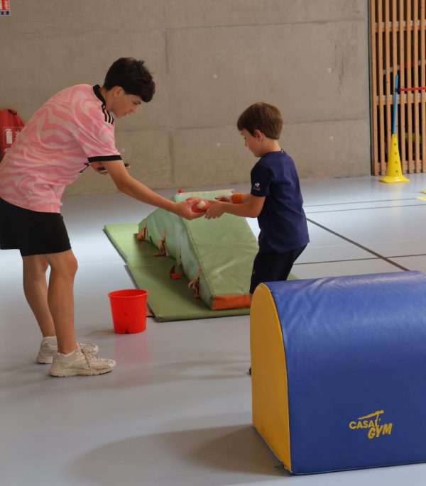 Maxence, jeune stagiaire apprend le basket à un enfant venu au cours d'une après-midi découverte.